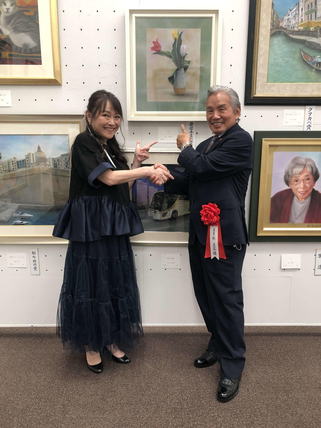 受賞作品の前で握手を交わす井上あずみ（左）と朴正文氏
