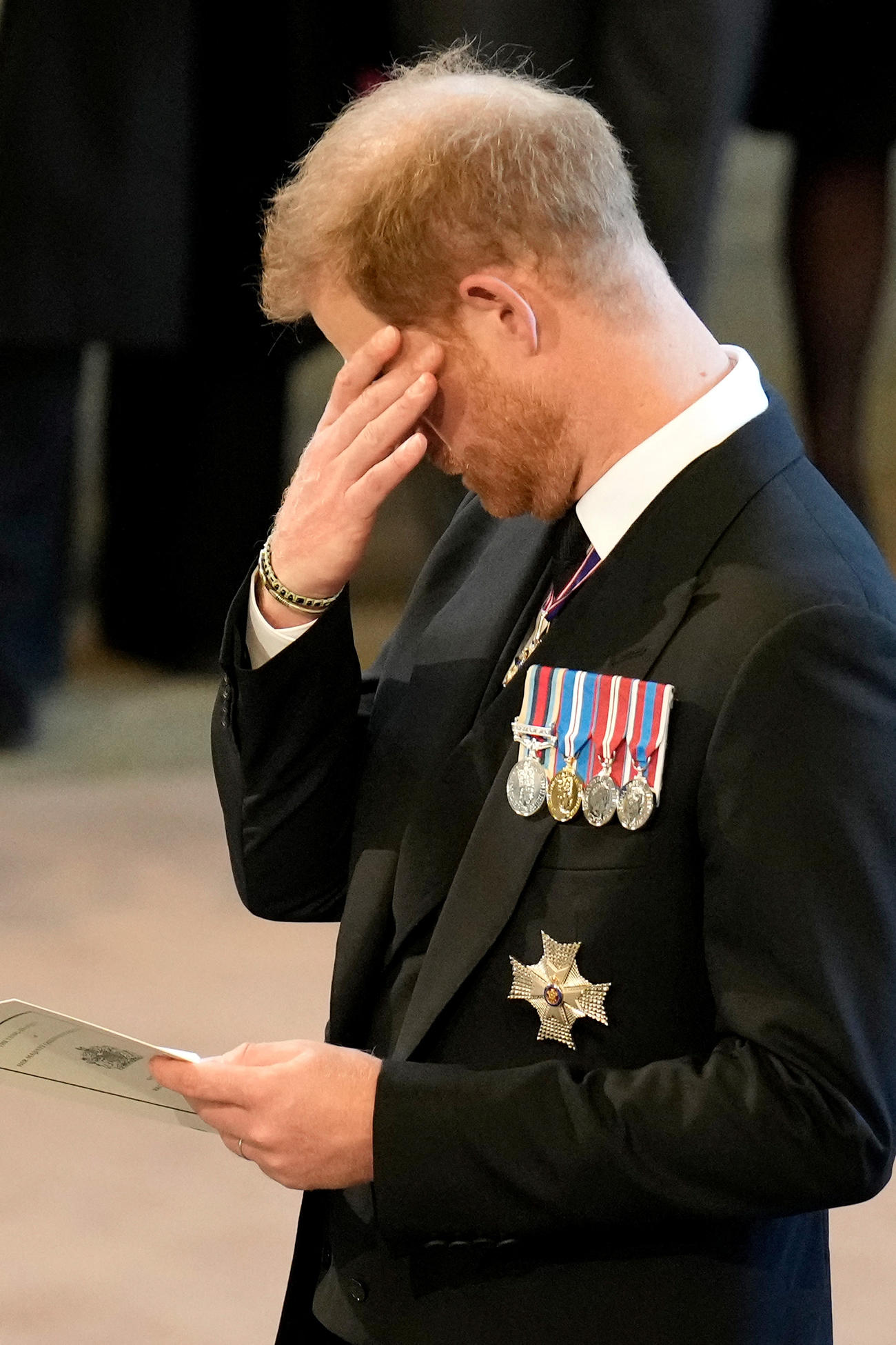 22年9月14日、エリザベス女王のひつぎがウェストミンスター・ホールに運ばれた際に、涙をぬぐうような仕草を見せたヘンリー王子（ロイター）