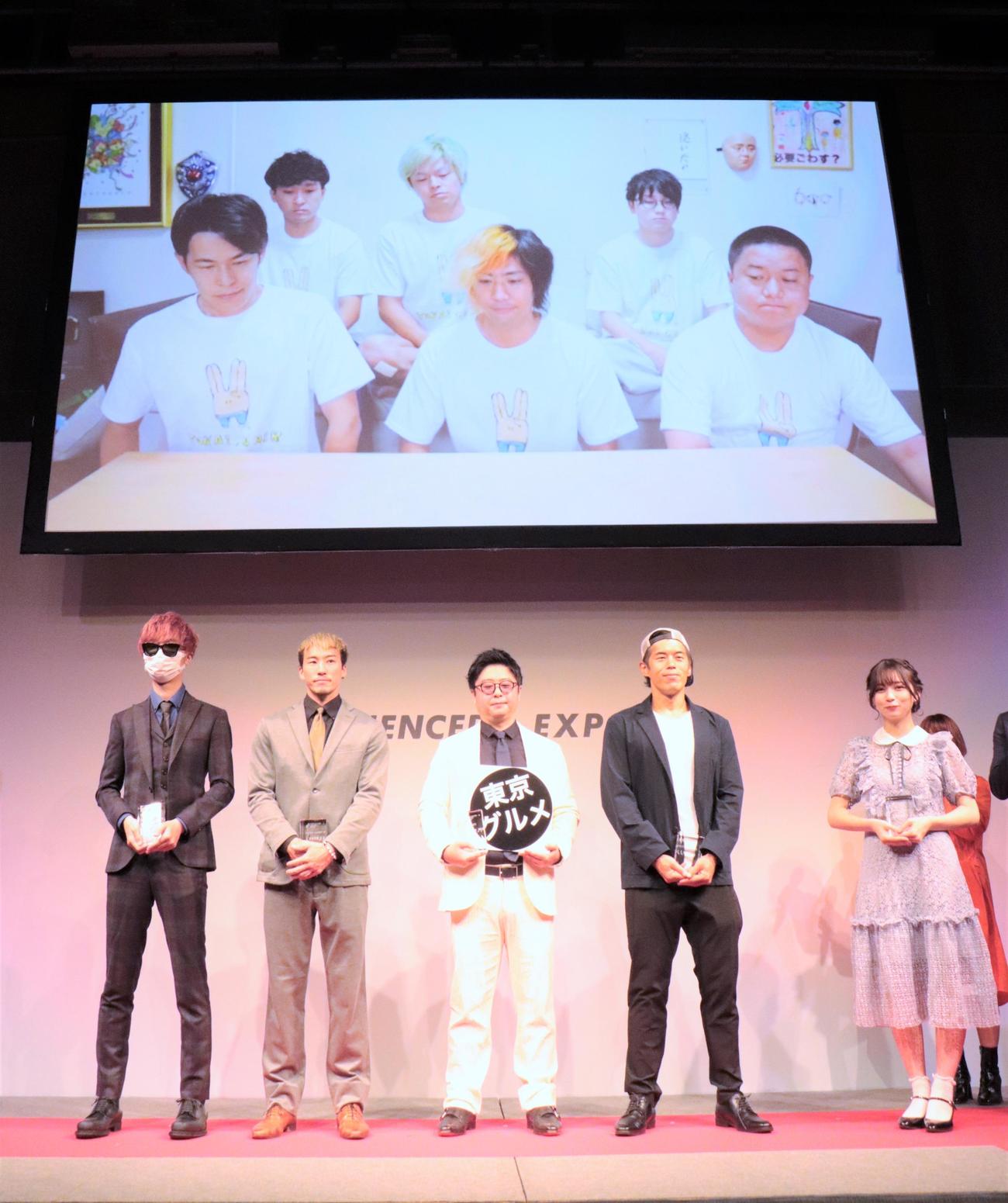 「第4回　Influencer’s EXPO 2022 A／W」で「インフルエンサーズアワード2022」を受賞した、ステージ上左からカラフルピーチ、イヌイサン、東京グルメのマネジャー、Kazu、nanakoななこ、スクリーン前列左から東海オンエアのりょう、てつや、ゆめまる、後列左からとしみつ、しばゆー、虫眼鏡（撮影・藤塚大輔）