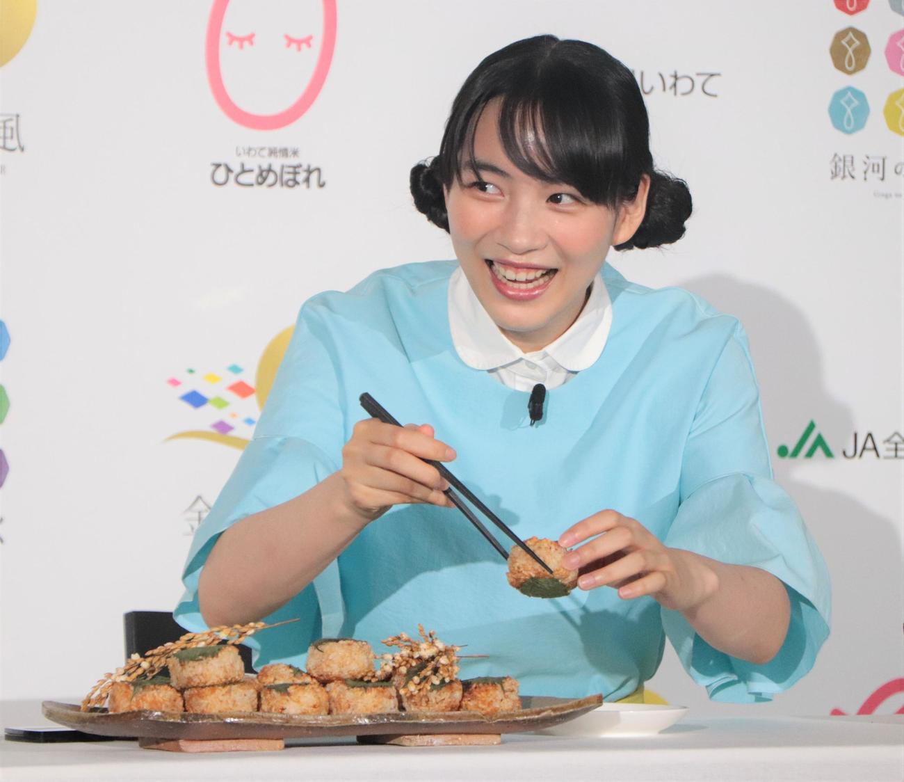 「2022『いわて純情米』新CM発表イベント」で焼きおにぎりを食べようとするのん（撮影・藤塚大輔）