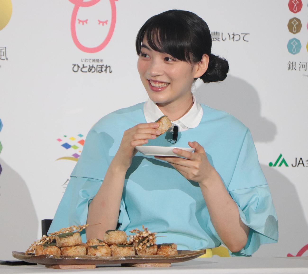 「2022『いわて純情米』新CM発表イベント」で焼きおにぎりを食べて笑顔を浮かべるのん（撮影・藤塚大輔）