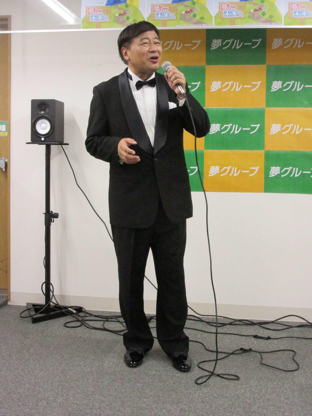 エナメルの靴を含め総額14万円のタキシード姿で会見に臨む夢グループ石田重廣社長（30日、東京・音羽の夢グループ本社で）