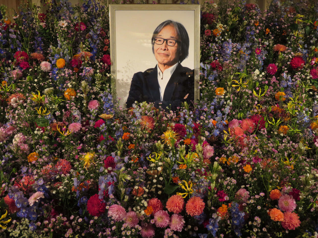 多くの花で遺影を包み込むようにしつらえられた、河村光庸さんのお別れの会の祭壇（撮影・村上幸将）