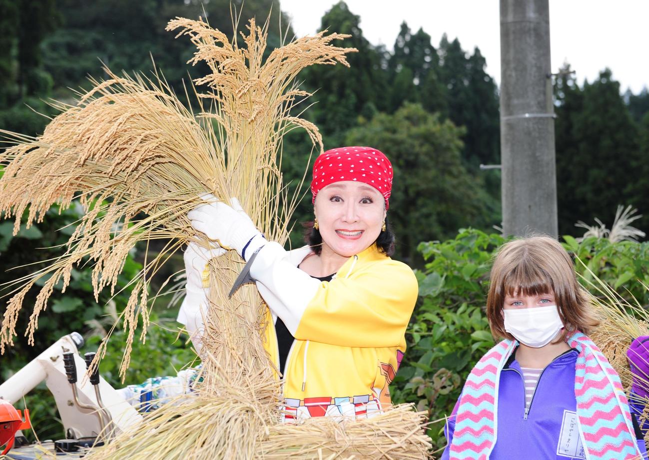 山古志小の児童と一緒に脱穀をする小林幸子