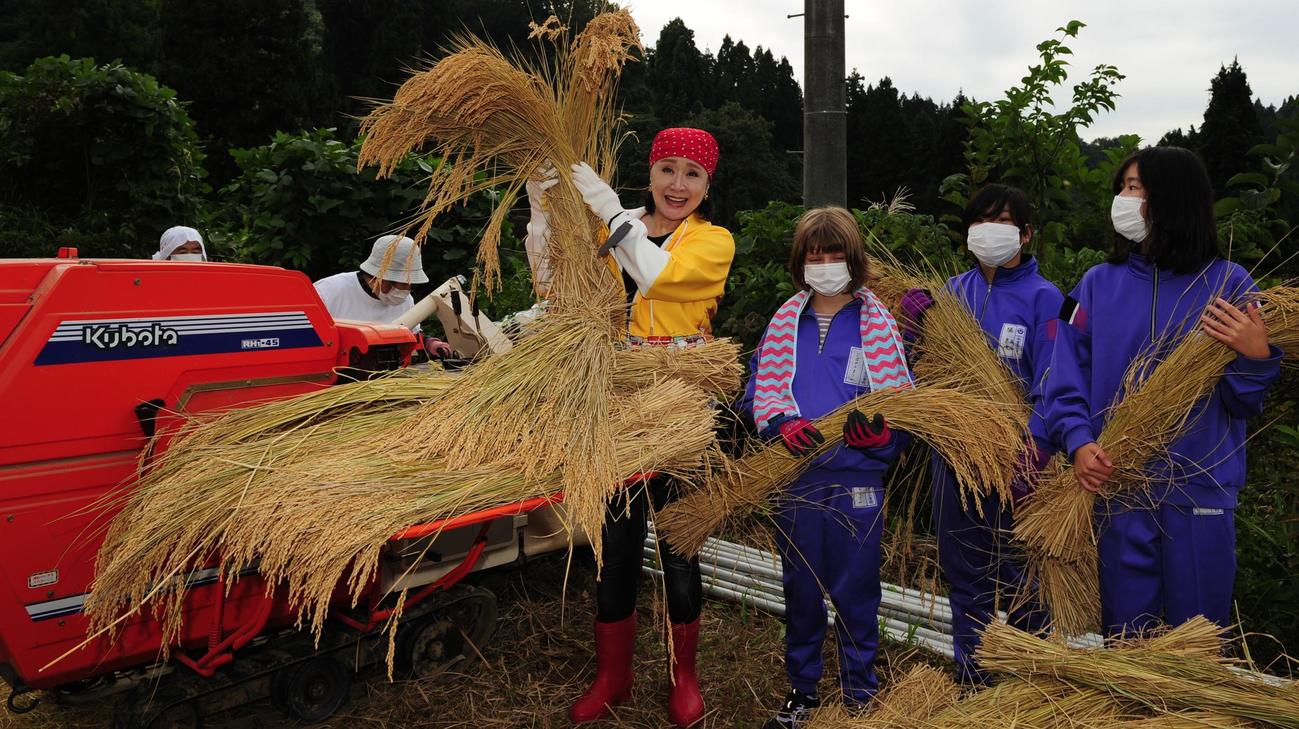 山古志小の児童らと一緒に脱穀をする小林幸子