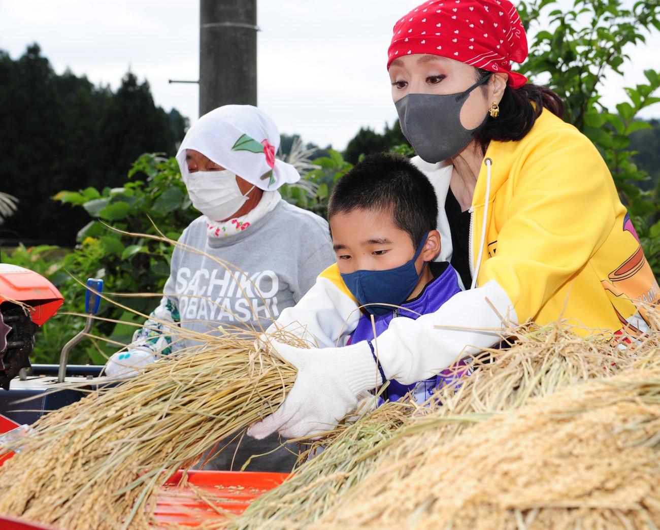 山古志小の児童と一緒に脱穀をする小林幸子