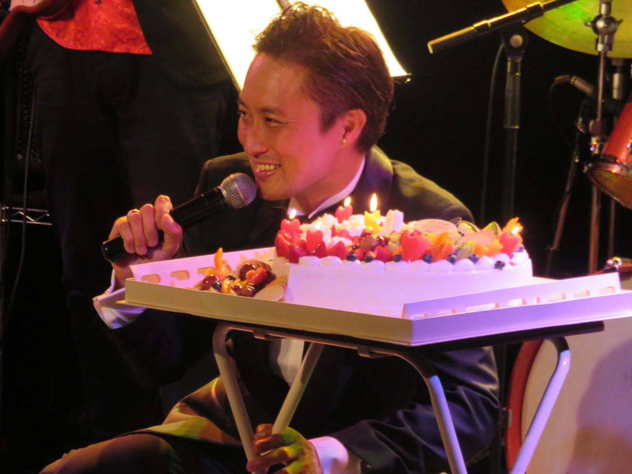 バースデーケーキを前に笑顔を見せるケニー大倉