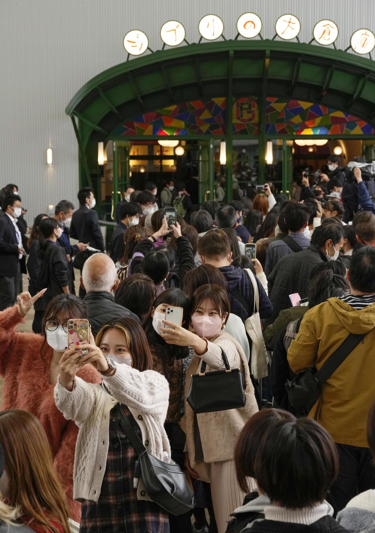 ジブリパークがオープンし、「ジブリの大倉庫」エリアの入り口前で写真を撮る人たち＝1日午前、愛知県長久手市（共同）