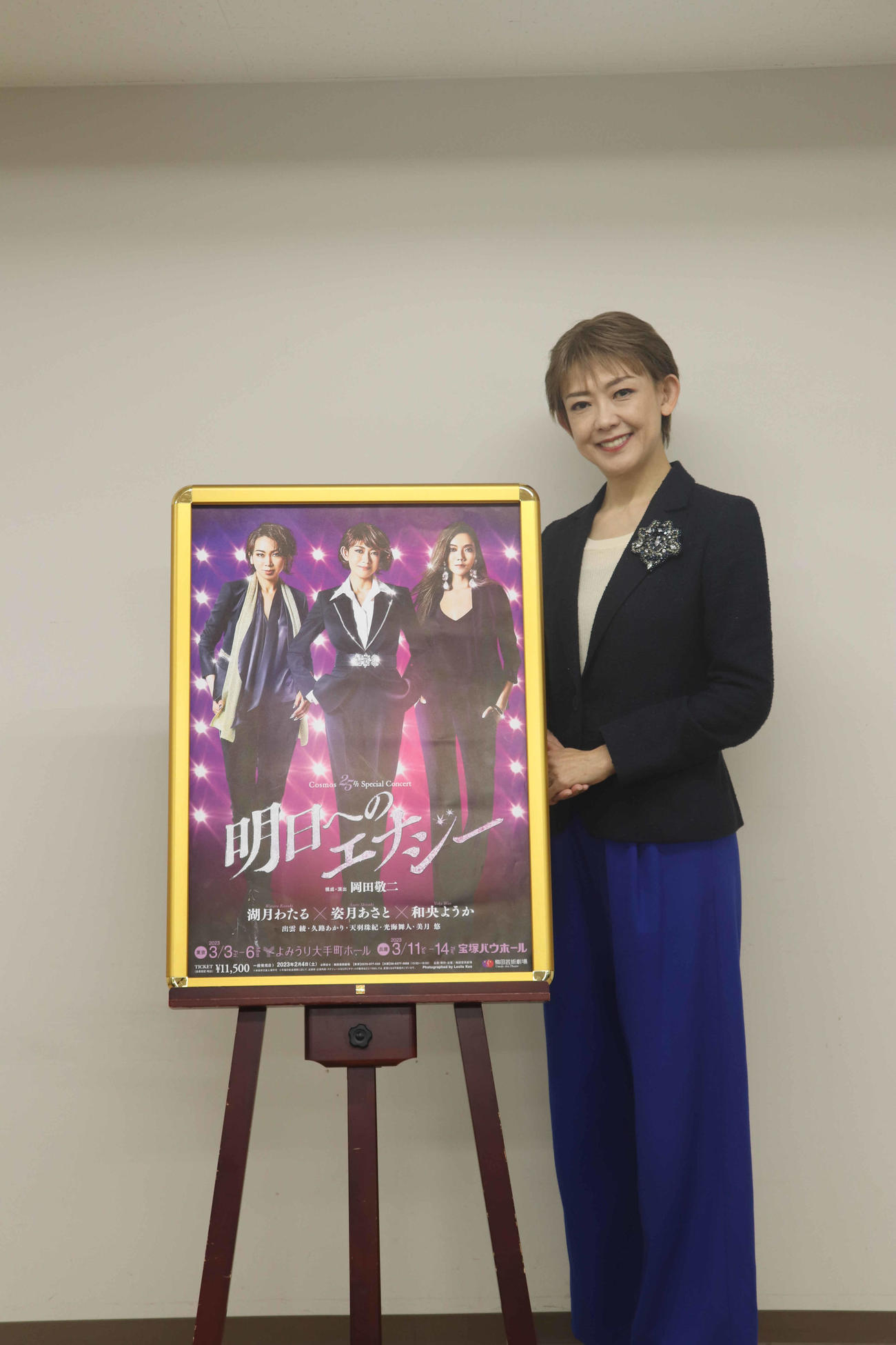 ポスターの横に立ち、笑う姿月あさと（撮影・竹本穂乃加）＝2022年12月8日、大阪・梅田芸術劇場