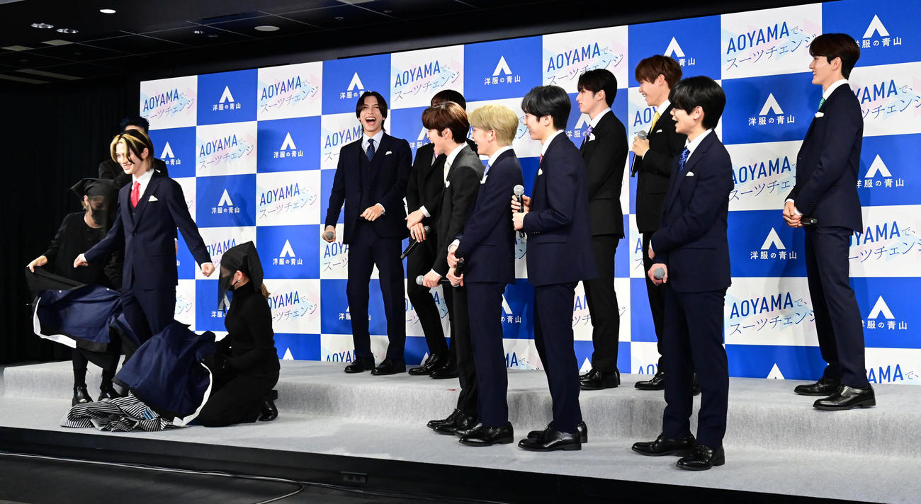「洋服の青山　新CM発表会」で20歳を迎え袴姿で臨んだ松田迅（左）のスーツへの早着替えを見守るINIのメンバーたち（撮影・小沢裕）