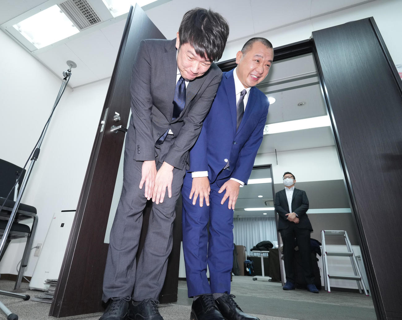会見を終え深々と頭を下げ引き揚げるTKO木本武宏（左）と木下隆行（撮影・菅敏）