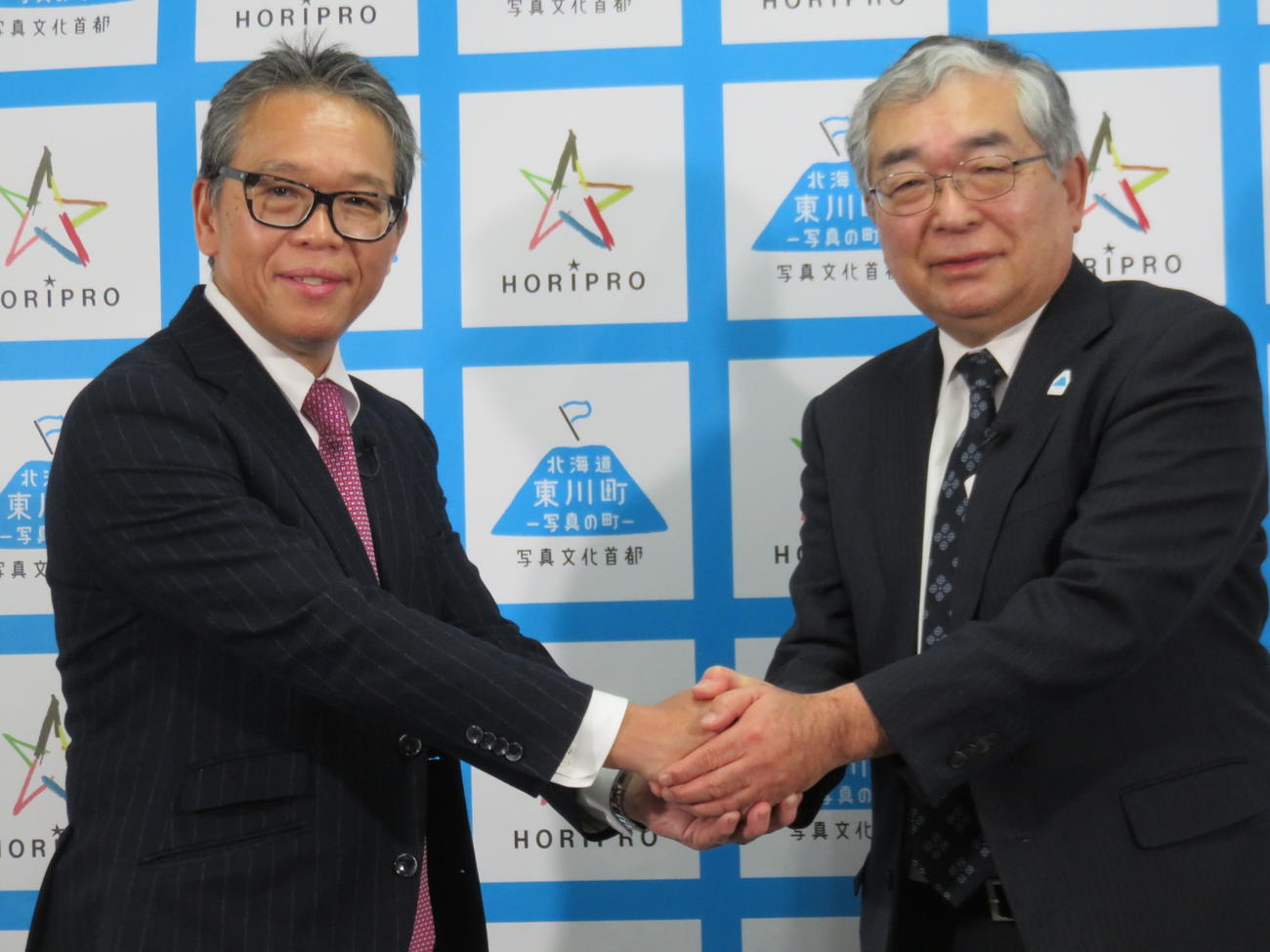 オフィシャルパートナー協定を結んだ海道・東川町の松岡市郎町長（右）とホリプロ菅井敦社長