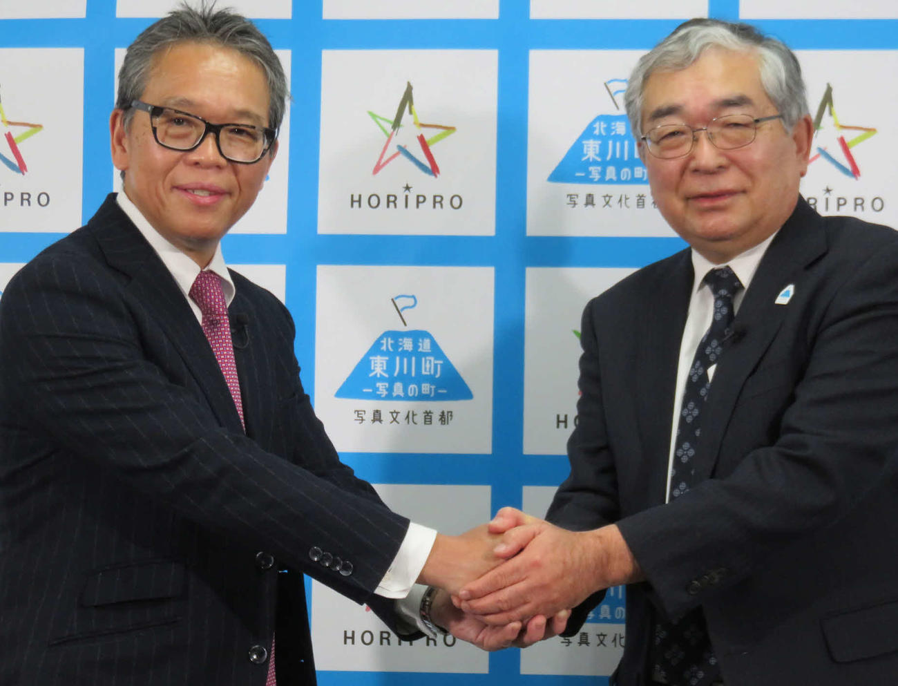 オフィシャルパートナー協定を結んだ海道・東川町の松岡市郎町長（右）とホリプロ菅井敦社長