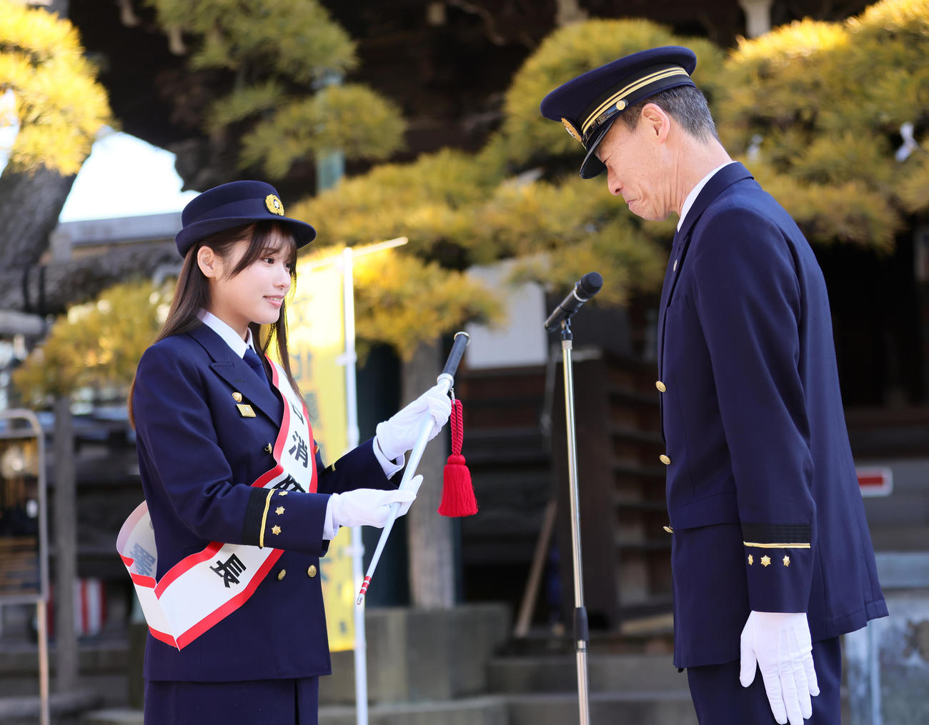 金町消防署の「一日消防署長」を務めた古田愛理（左）は五十嵐潤一署長から指揮棒を受け取る（撮影・足立雅史）