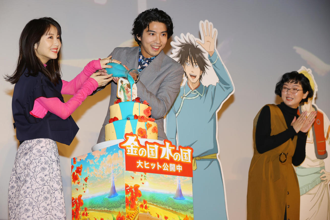 映画「金の国　水の国」公開記念舞台あいさつで、映画に登場する水路をイメージした水色のソースをカラードリップケーキにかける左から浜辺美波、賀来賢人。右端は渡辺こと乃監督（撮影・野上伸悟）