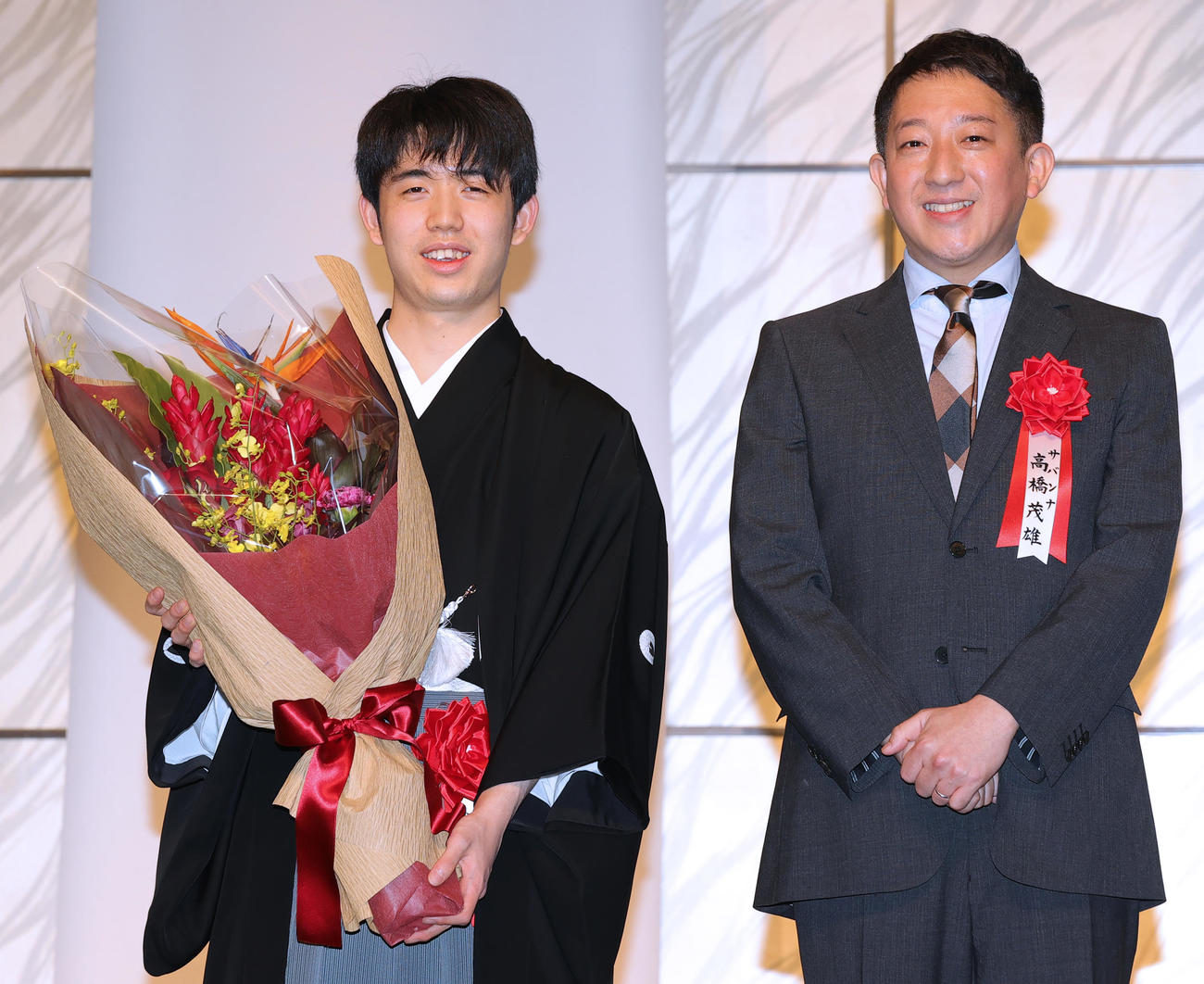 第35期竜王就位式で、サバンナ高橋茂雄（右）から花束を受け取り笑顔の藤井竜王（撮影・野上伸悟）