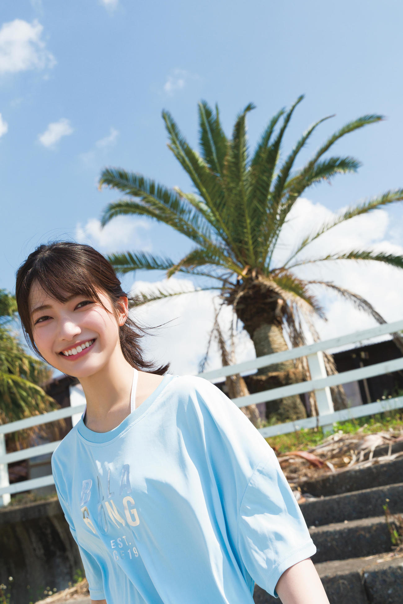 櫻坂46大園玲ファースト写真集先行カット。鹿児島の海沿いで水色シャツ姿で笑顔