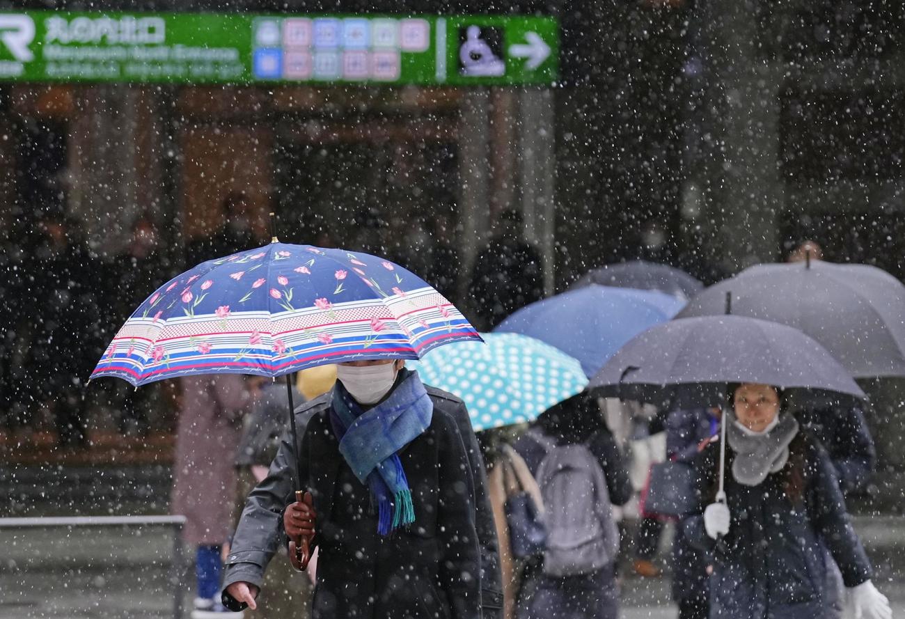 雪が舞う中、JR東京駅前を歩く通勤客（共同）