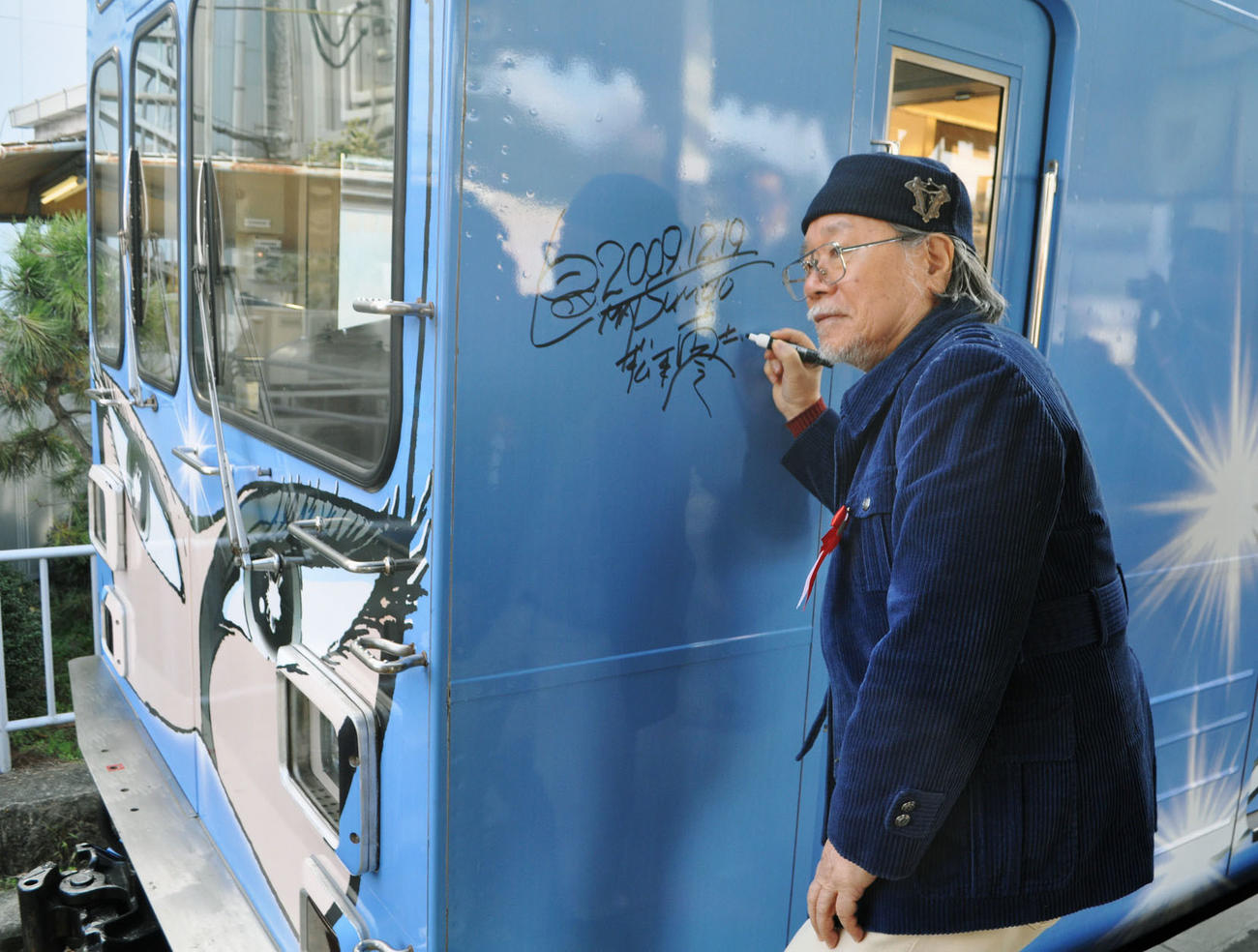 2009年12月、自身がデザインした「忍者列車」にサインをする松本零士さん（共同）
