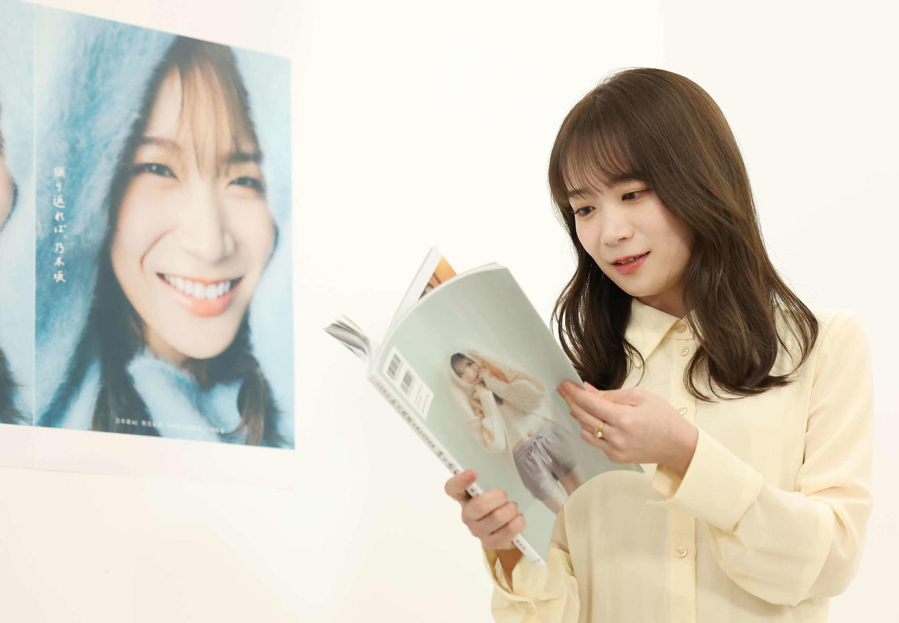 写真集を手にお気に入りのカットを選ぶ秋元真夏（撮影・丹羽敏通）
