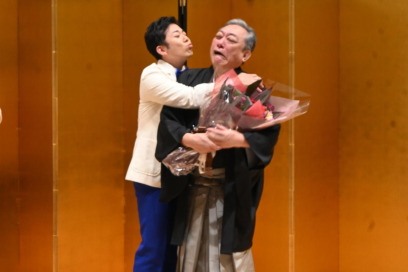 藤山扇治郎（左）から花束を贈呈され、ご苦労さまのキスを迫られる渋谷天外（撮影・松浦隆司）