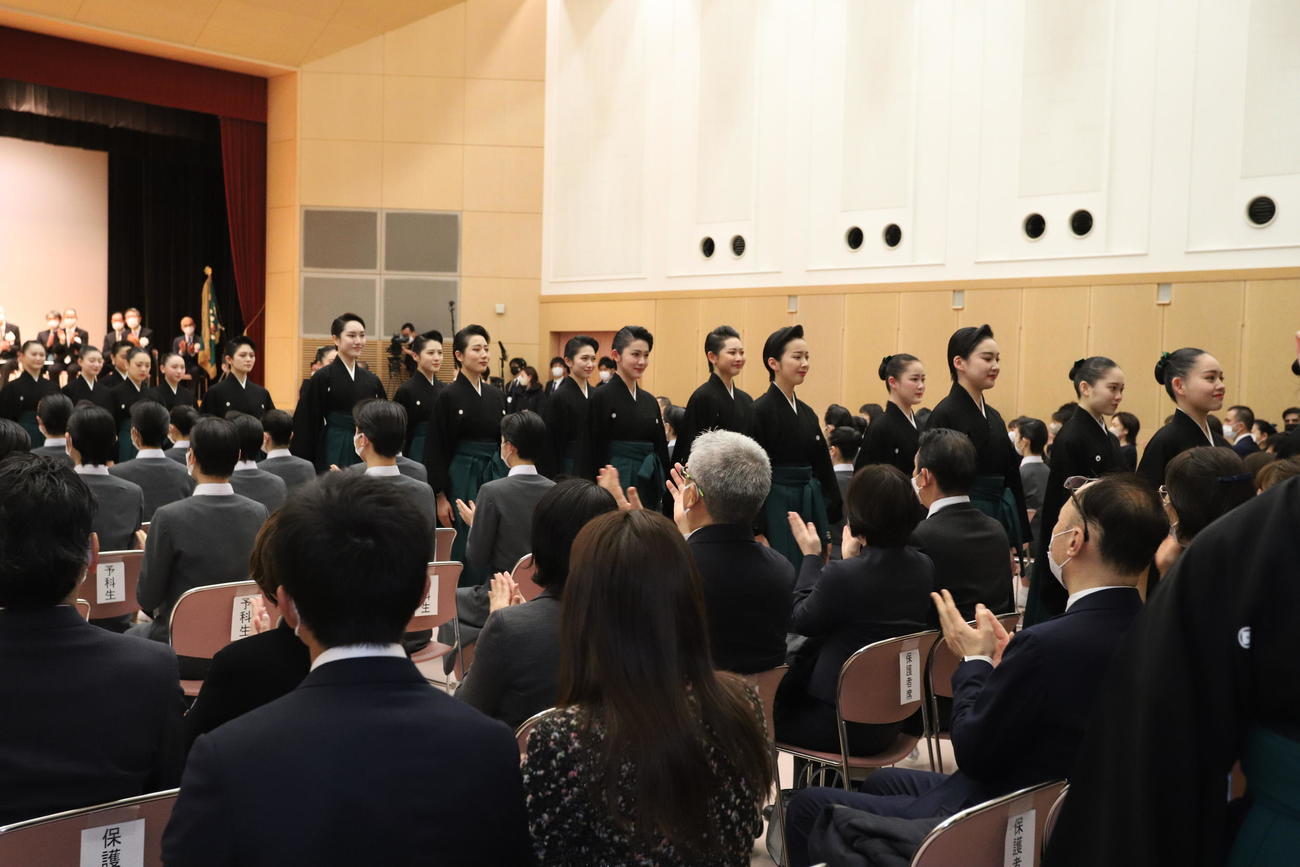 マスクを外して式典を終え、退場する宝塚音楽学校109期生ら