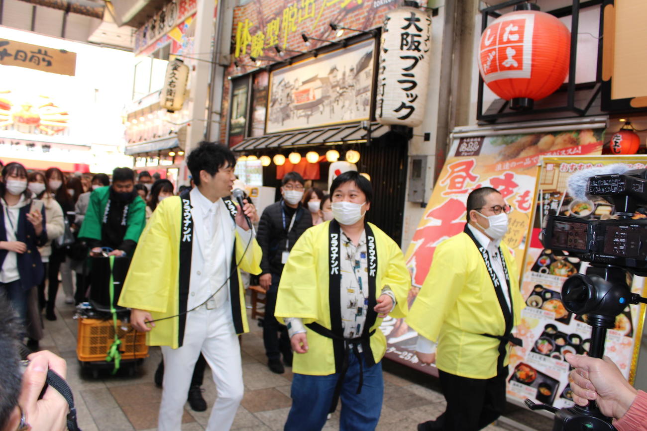 商店街をパレードするノンスタイル石田（左）と、右へニッポンの社長・ケツ、ネルソンズ和田まんじゅう