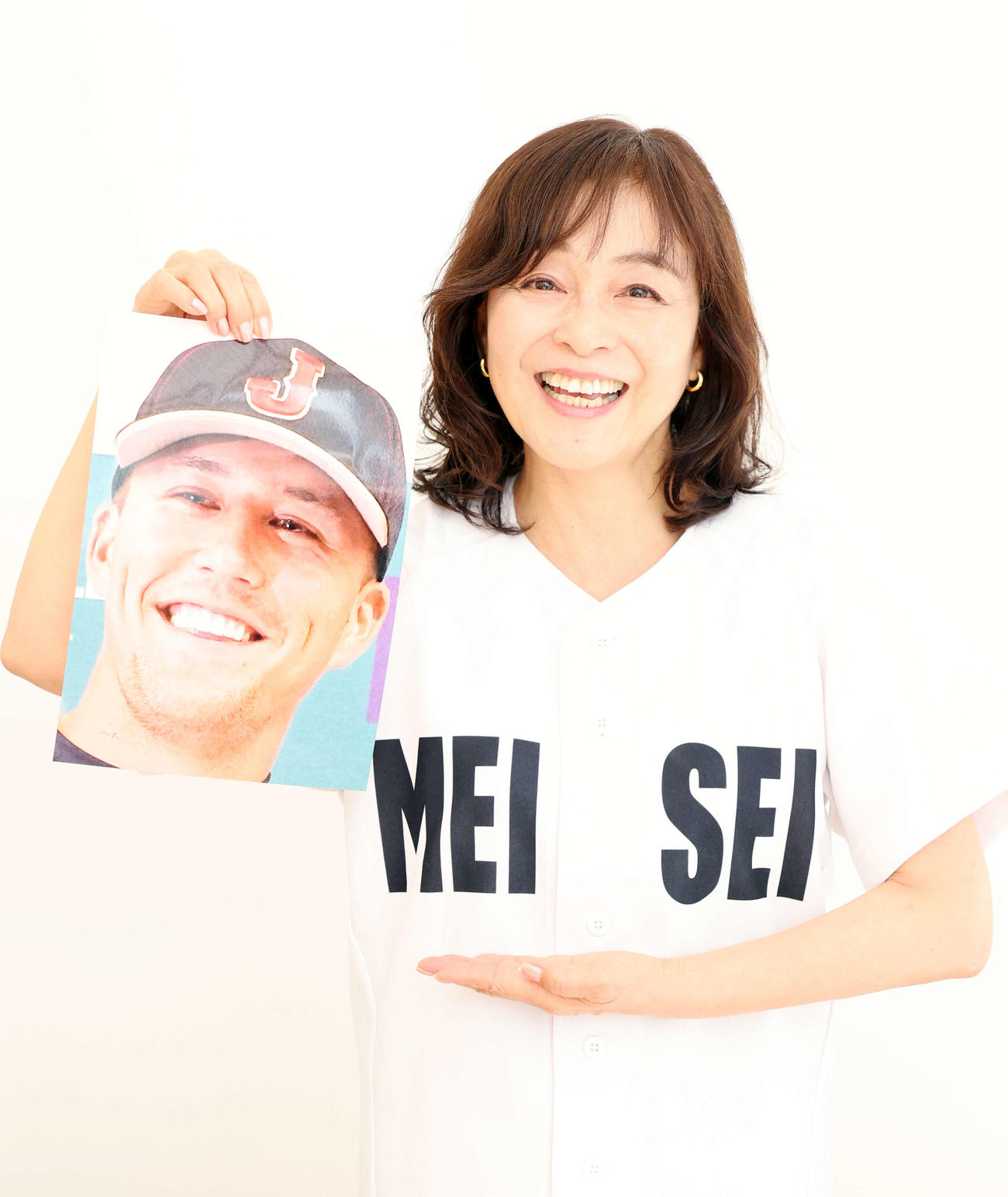 漫画「タッチ」の明青学園のユニホームを着て、たっちゃんことヌートバーの写真を手に笑顔を見せる日高のり子（撮影・浅見桂子）
