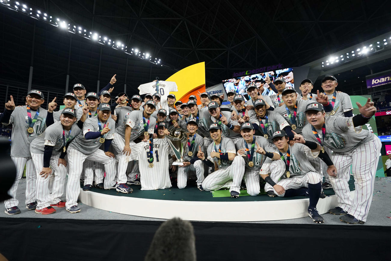 3年ぶりに世界一となり優勝トロフィーを抱える栗山監督（中央）を中心に記念撮影する日本の選手たち（AP）