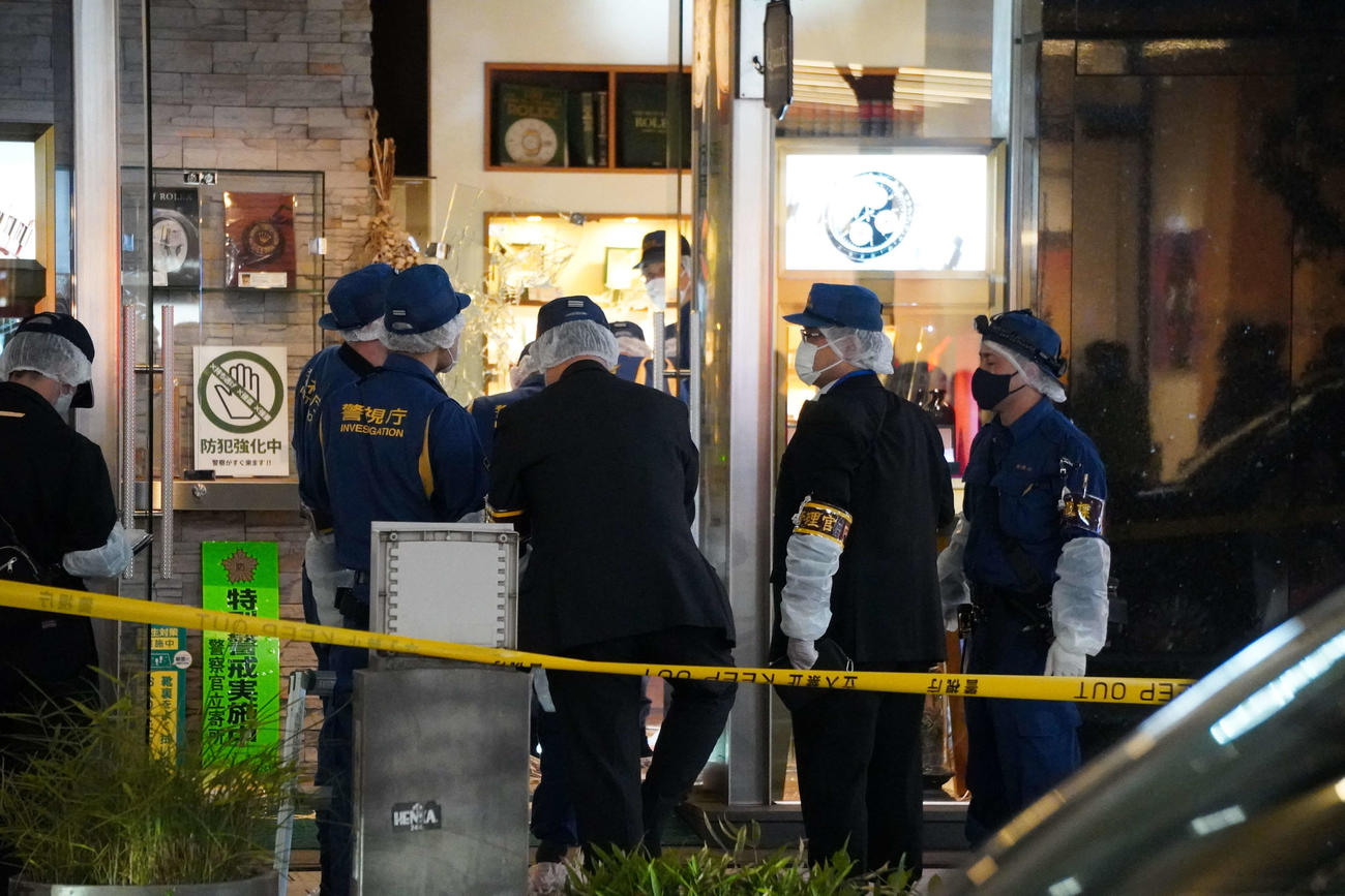 強盗が入った時計店を調べる警察官。ショーケースのガラスは破損している（撮影・沢田直人）