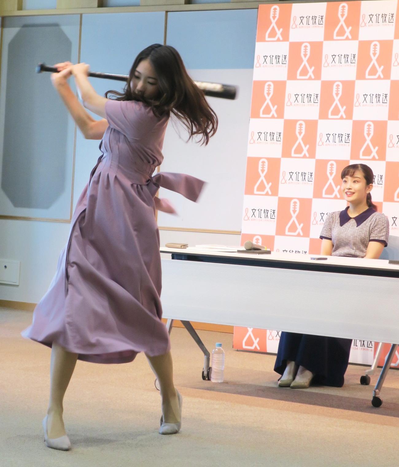 豪快な素振りで意気込みを披露する久保朱莉アナウンサー。後ろは甲斐彩加アナ