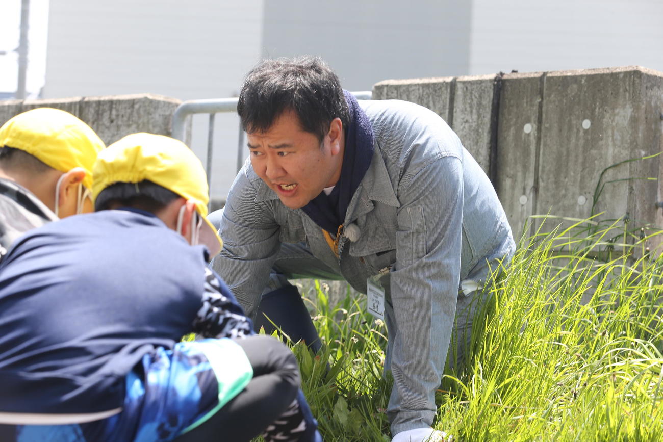 安村（中央）は、気に寄り掛かり、なぜか小学生たちと見下ろしながらじゃがいもの植え方を説明（撮影・中島洋尚）　