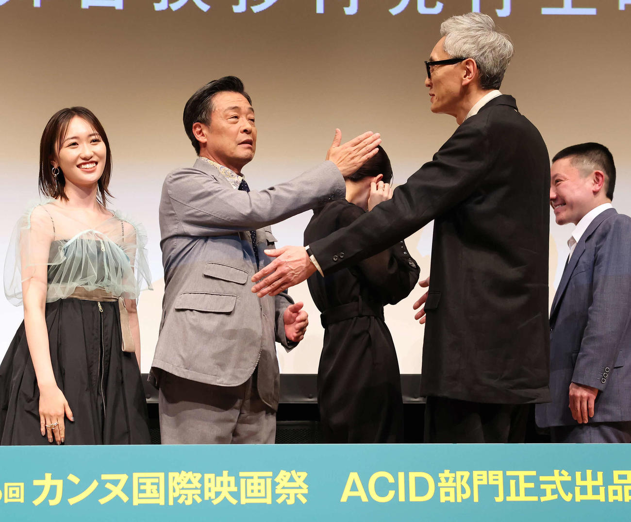 フォトセッションの途中でイヤリングが外れた吉本実憂をガードする光石研と松重豊（撮影・丹羽敏通）