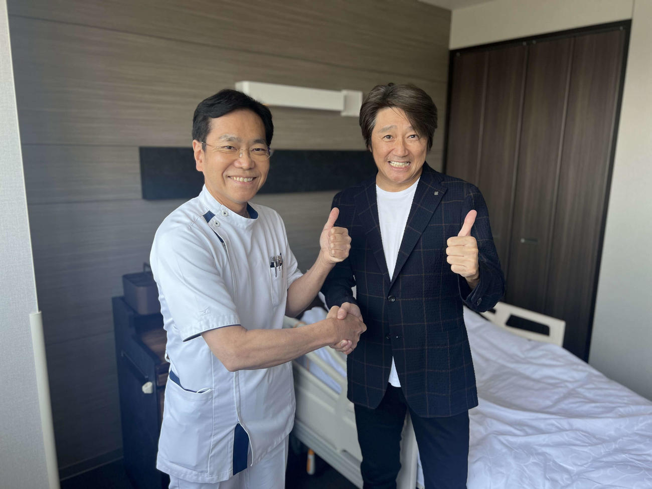 執刀医の牧田総合病院朝本俊司医師（左）と握手する近藤真彦