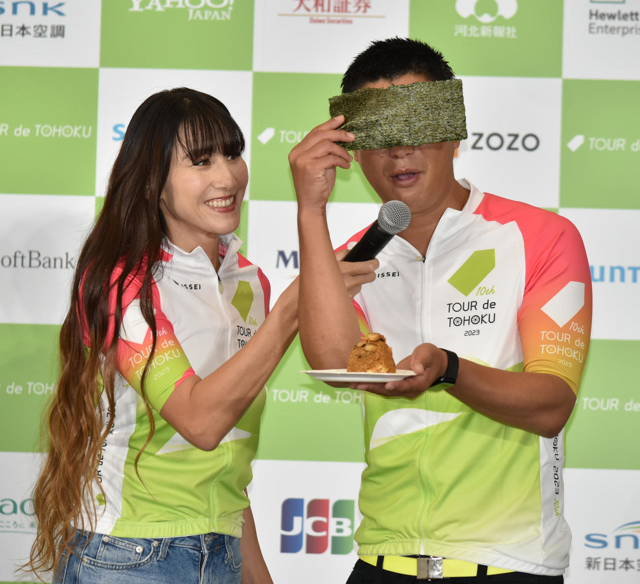 「ツール・ド・東北　2023」記者発表会で「エイド食」の穴子おにぎりを試食する際に、のりでボケるパンサー尾形貴弘。左は食リポをサポートする道端カレン
