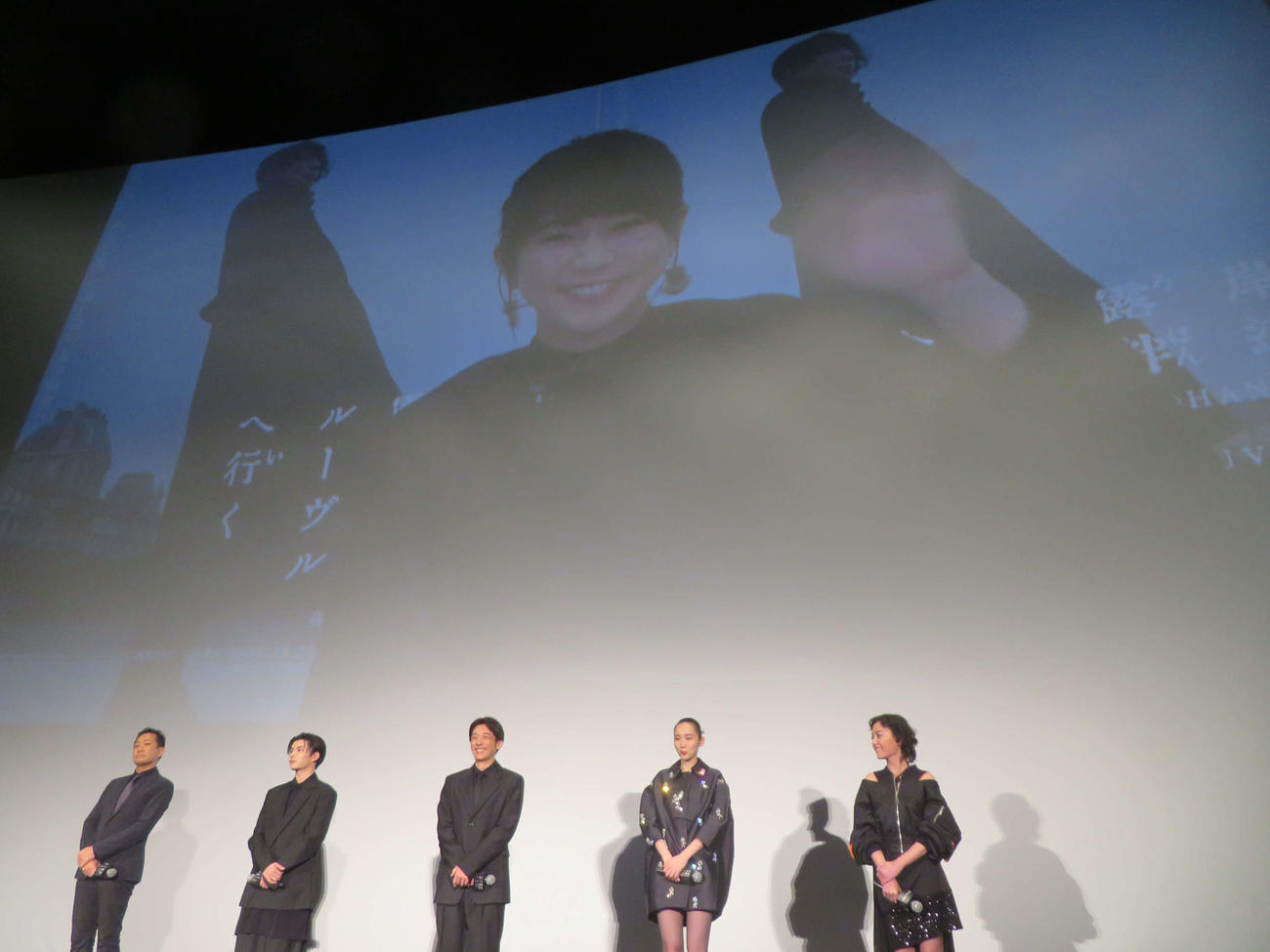 映画「岸辺露伴　ルーヴルへ行く」公開記念舞台あいさつに登壇した、左から渡辺一貴監督、なにわ男子の長尾謙杜、高橋一生、飯豊まりえ、美波とリモート参加し、スクリーンから手を振る木村文乃（撮影・村上幸将）