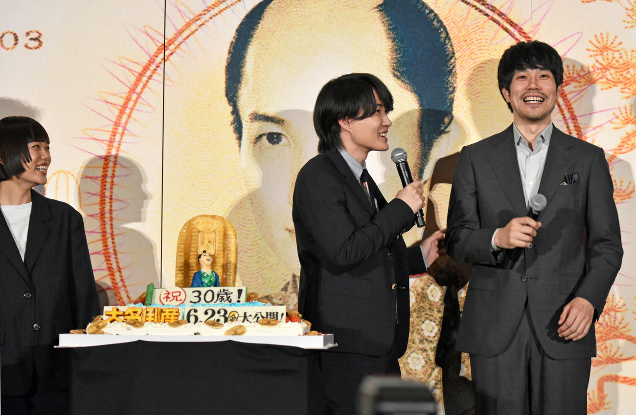 映画「大名倒産」完成披露試写会で主演神木隆之介（中央）へのサプライズバースデーケーキが登場も、1台のテレビカメラを見続ける松山ケンイチ。左端は杉咲花