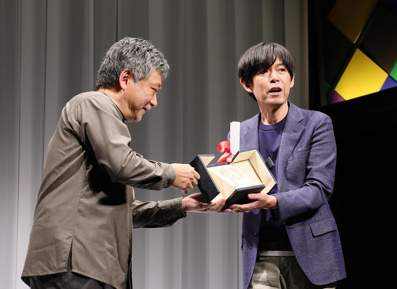カンヌ国際映画祭「脚本賞」を受賞した坂元裕二氏（右）は是枝裕和監督からトロフィーを受け取る（撮影・足立雅史）