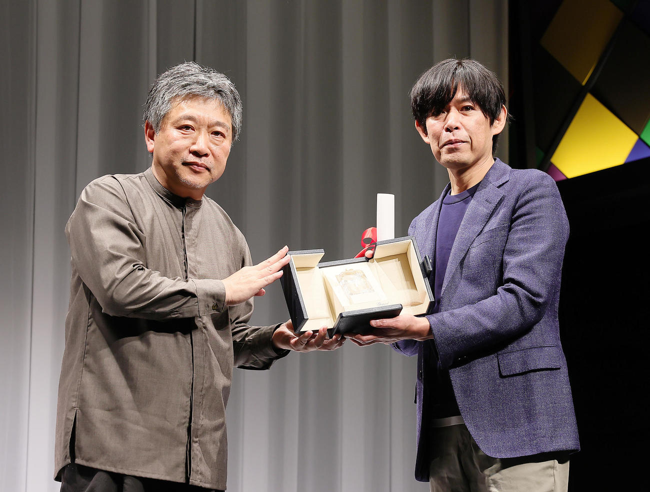 カンヌ国際映画祭「脚本賞」を受賞した坂元裕二氏（右）は、帰国した是枝裕和監督からトロフィーを受け取る（撮影・足立雅史）