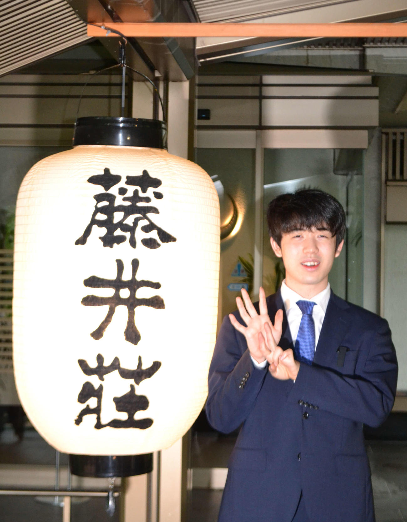 藤井荘のちょうちんの横で史上最年少7冠の「7」を表現する藤井聡太名人