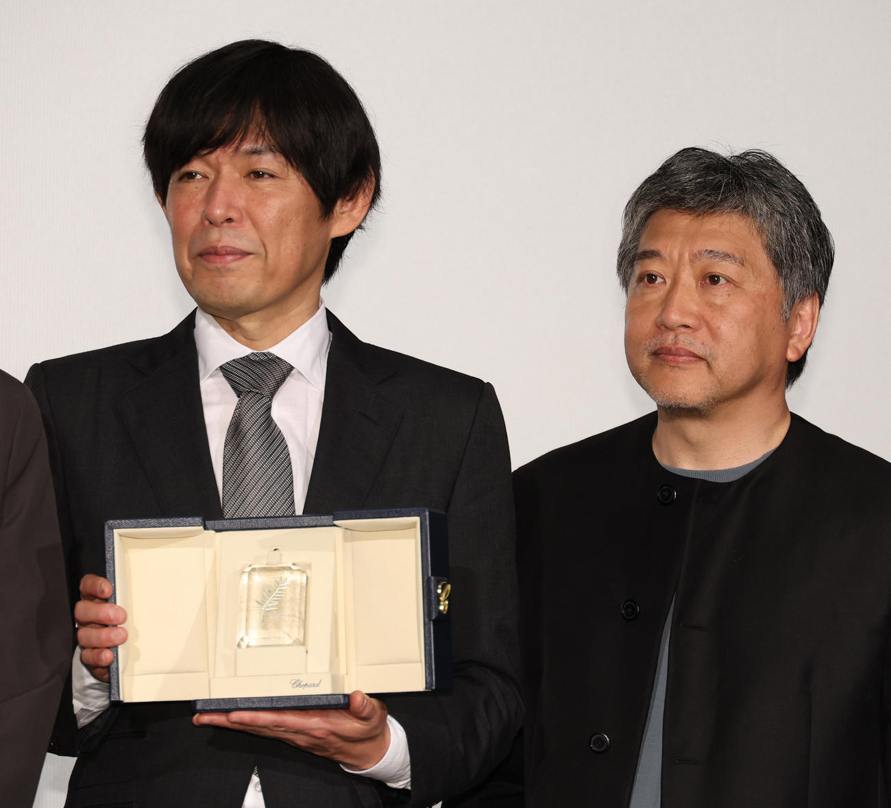 映画「怪物」初日舞台あいさつでカンヌ国際映画祭脚本賞のトロフィーを披露する坂元裕二氏。右は是枝裕和監督（撮影・中島郁夫）