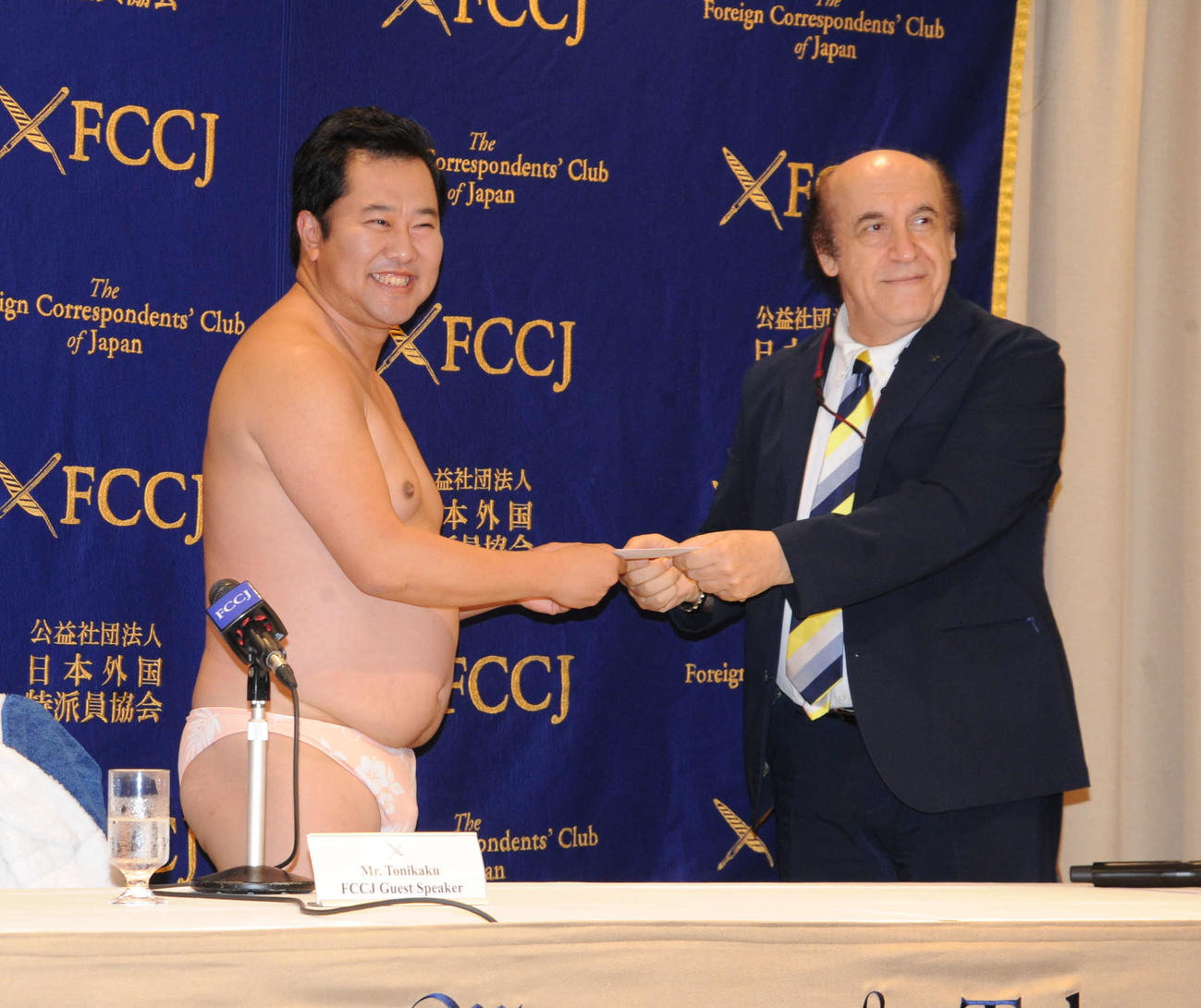 日本外国特派員協会で会見を行い、モデレーターを務めたアズハリ氏（右）から同協会会員証を受け取る、とにかく明るい安村（撮影・松尾幸之介）