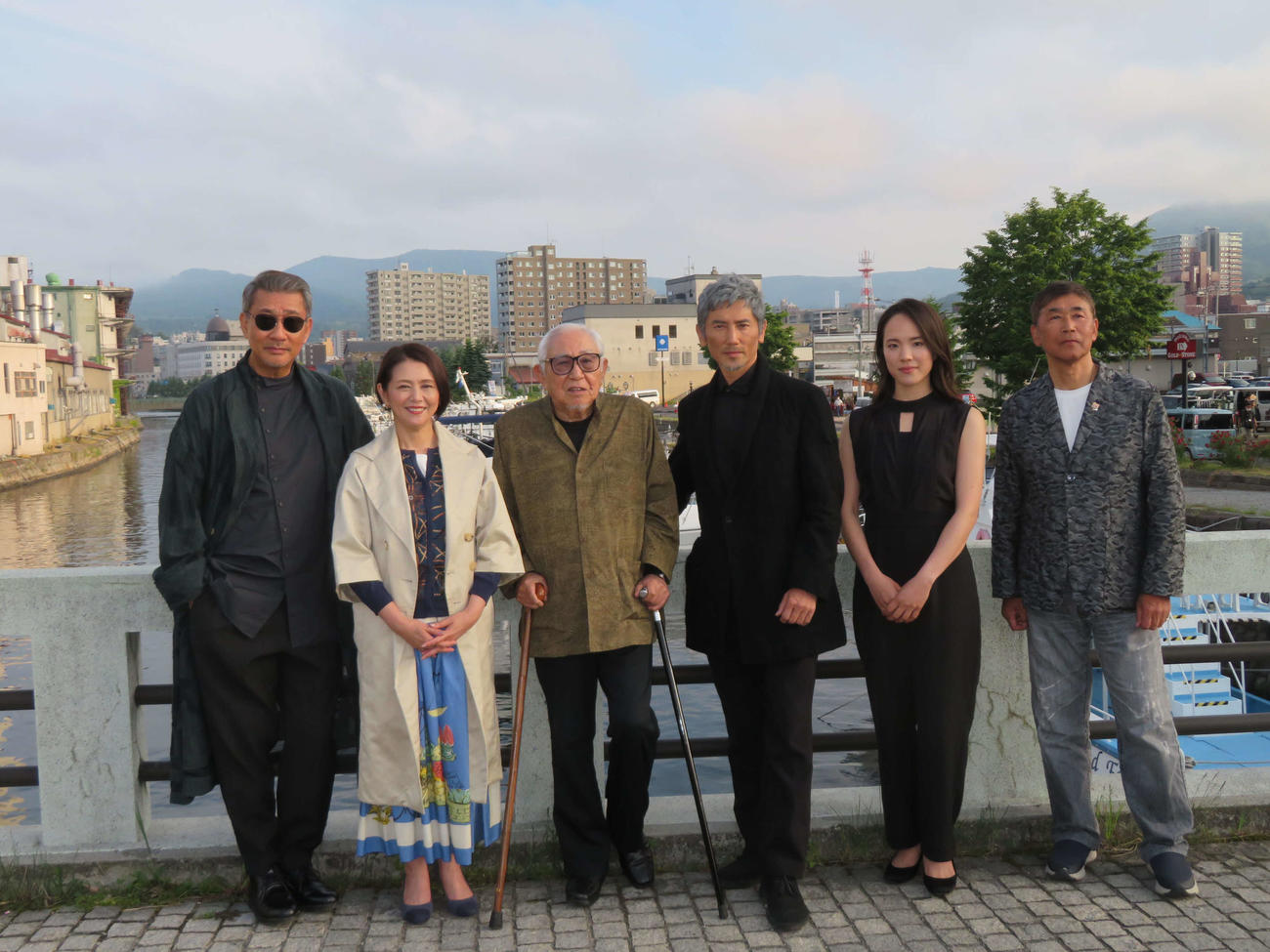 映画「海の沈黙」の撮影が行われている、北海道小樽市の名所・小樽運河を背に笑顔の、左から中井貴一、小泉今日子、倉本聰氏、本木雅弘、菅野恵、若松節郎監督（撮影・村上幸将）