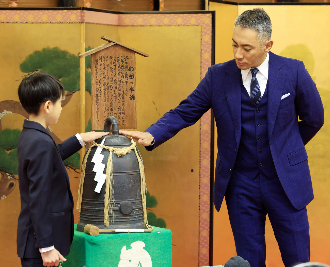 七月歌舞伎「神明恵和合取組　め組の喧嘩」の成功祈願に訪れた市川新之助（左）と市川團十郎は「め組の半鐘（はんしょう）」を触る（撮影・浅見桂子）