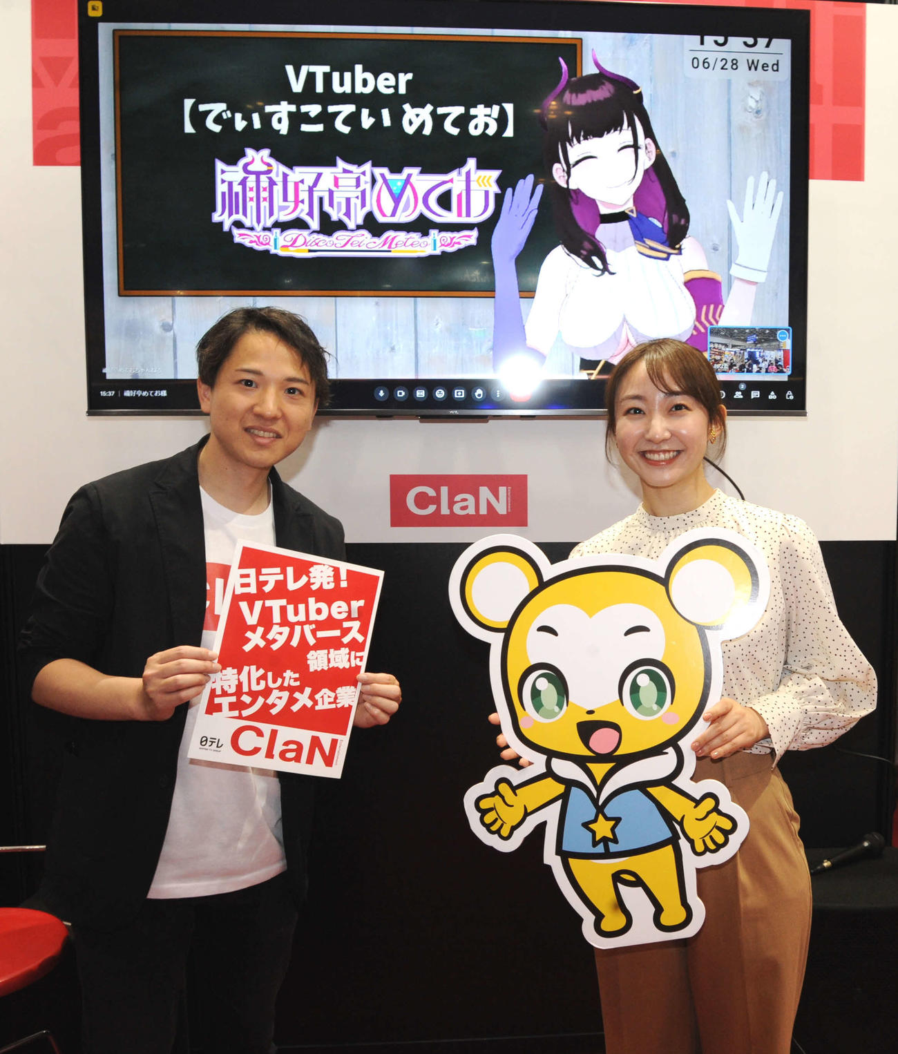 大規模国際総合展「コンテンツ東京」のClaN Entertainmentブースで対談した大井基行社長（左）と日本テレビの杉原凛アナウンサー。画面内はVTuberの禰好亭（でぃすこてい）めてお（撮影・松尾幸之介）