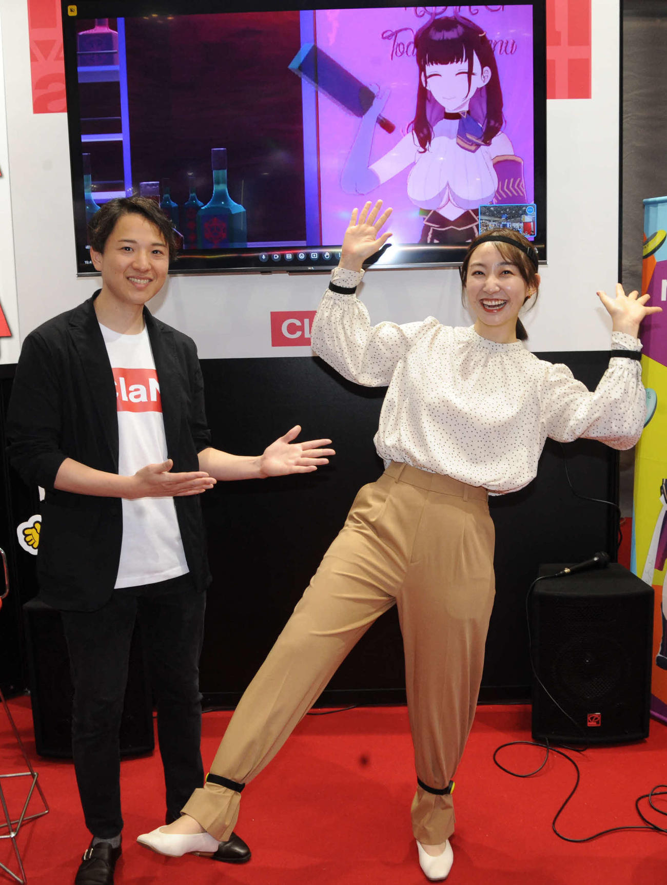 大規模国際総合展「コンテンツ東京」のClaN Entertainmentブースで、体にセンサーをつけてVTuber体験リポートを行った日本テレビの杉原凛アナウンサー（右）と大井基行社長。画面内はVTuberの禰好亭（でぃすこてい）めてお（撮影・松尾幸之介）