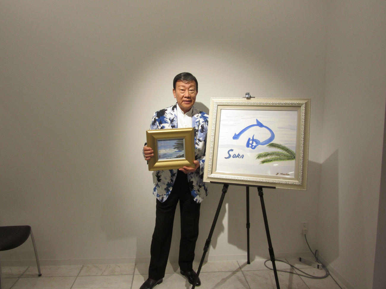 初の書画個展を開催した橋幸夫。持っているのが絵画「熱海風景」、右が書画展のテーマの書「宙（そら）」（5日、東京・有楽町マルイ）