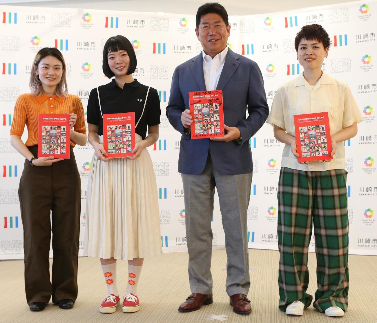 バンドスコアを贈呈し記念撮影に収まる、左から、SHISHAMOの松岡彩、宮崎朝子、福田紀彦川崎市長、吉川美冴貴