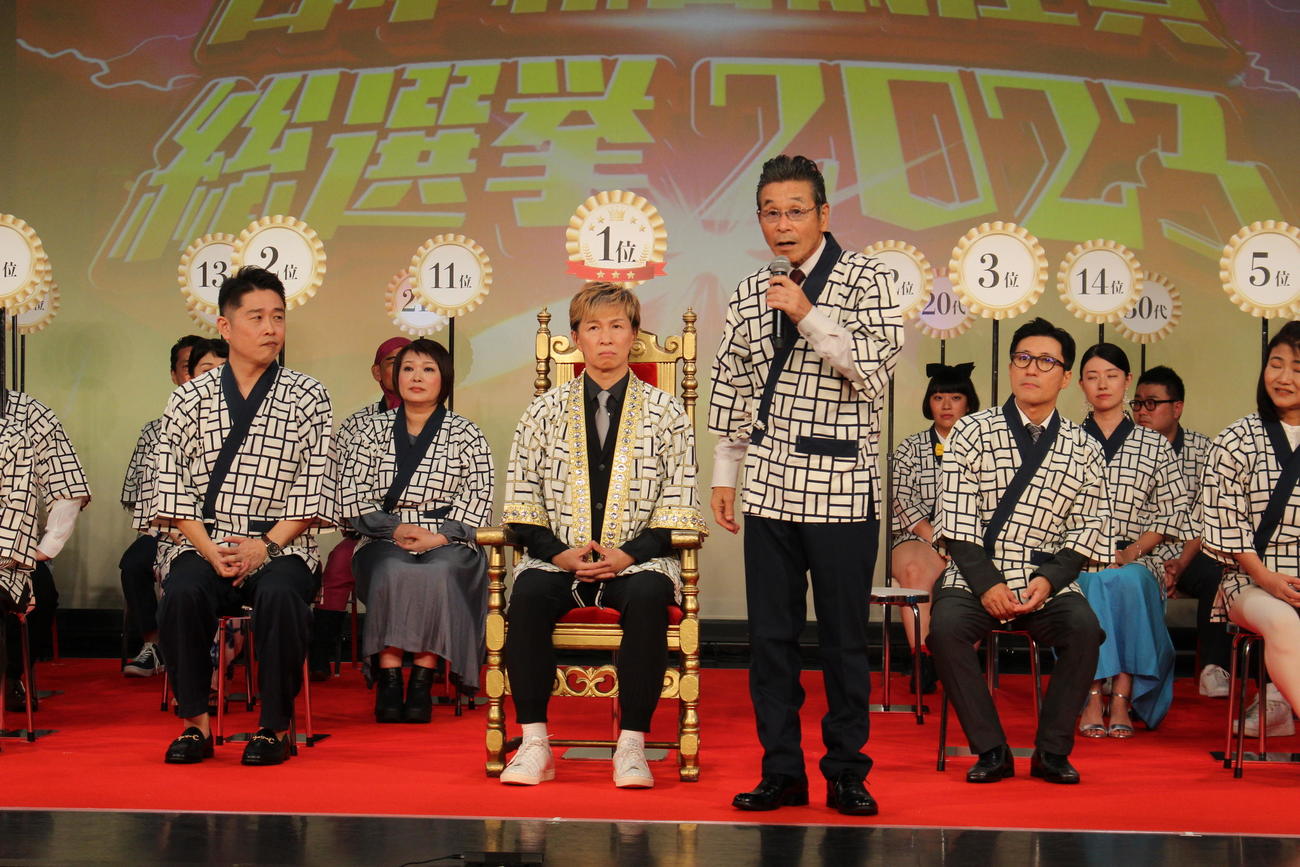 総選挙の結果を受け、コメントを述べる間寛平GM。その左は1位のアキ、さらに左は2位の千葉公平