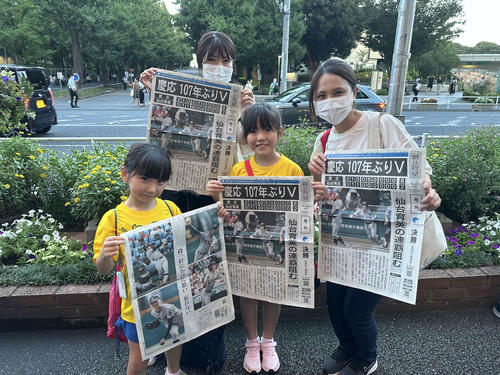 東急・日吉駅で慶応野球部の優勝を記念した号外を受け取り、笑顔を見せる親子ら（撮影・沢田直人）